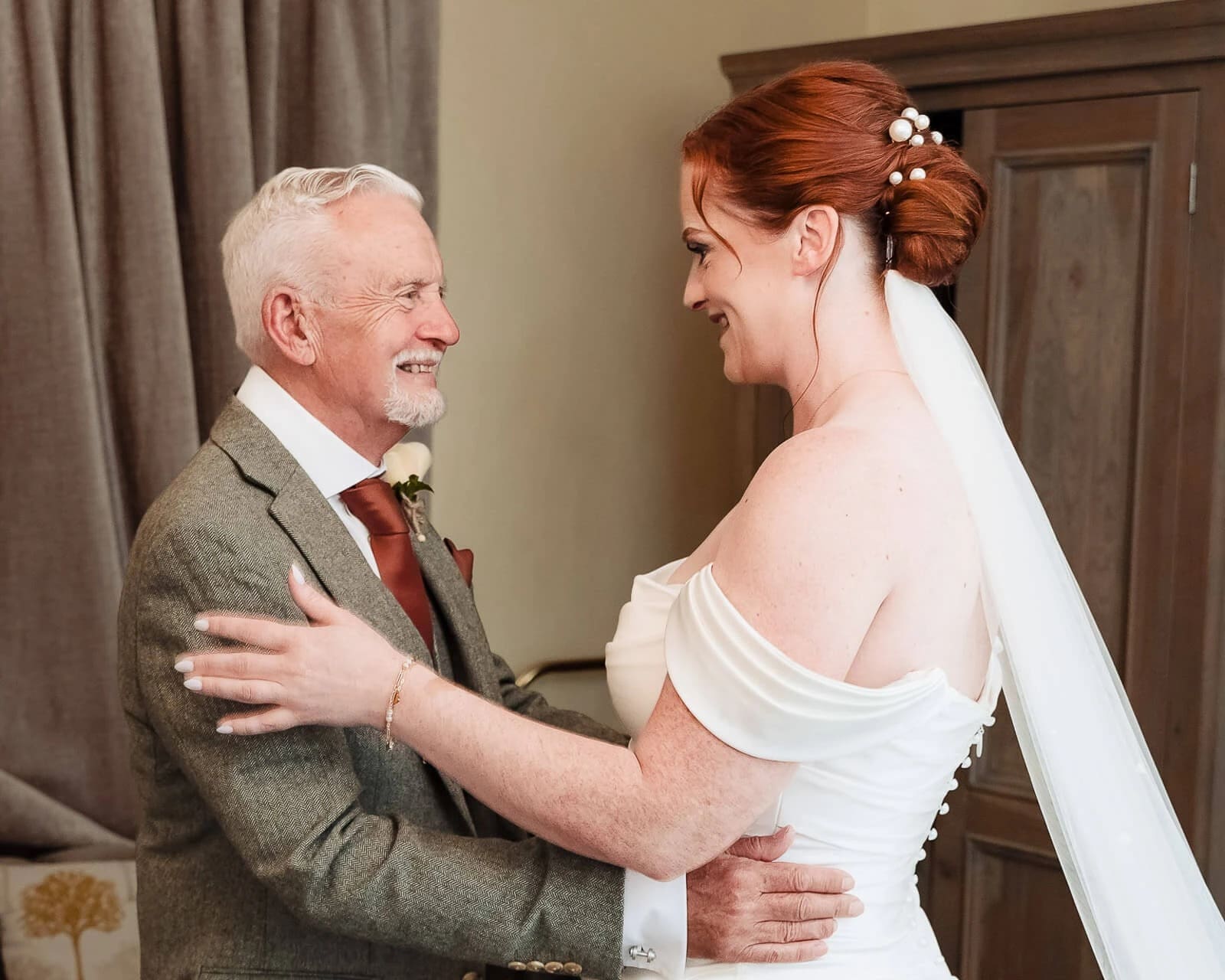 Bride and older man embrace and smile at each other during a first look moment. — Wedding at Hunters Hall, Norfolk
