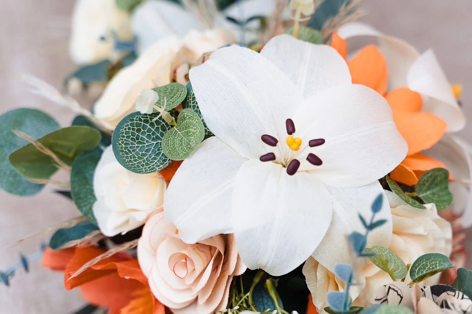 Close-up of a bridal bouquet with white flowers and orange blooms arranged together. — Wedding at Hunters Hall, Norfolk