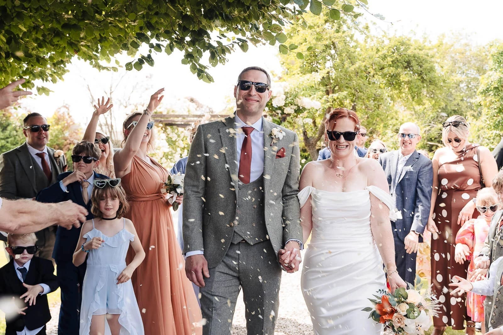 Newlyweds walk down the aisle as guests toss confetti in celebration. — Wedding at Hunters Hall, Norfolk