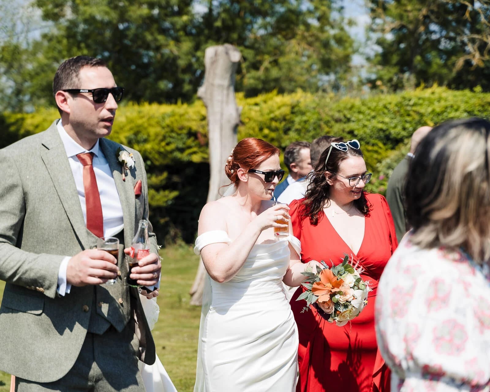 Wedding guests walking together across a lawn during the reception, conversing and holding drinks. — Wedding at Hunters Hall, Norfolk