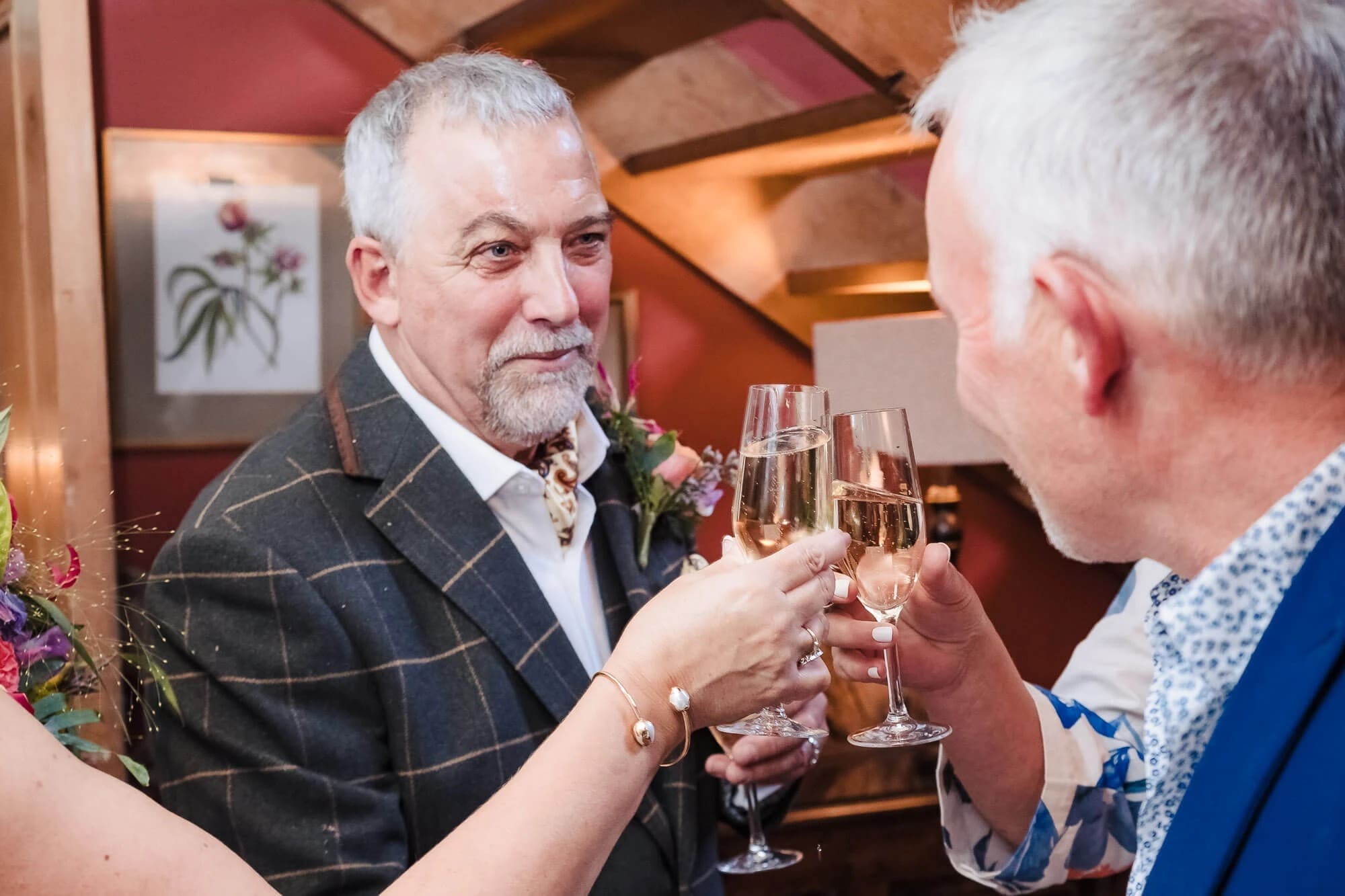 Two men toasting with champagne glasses at an indoor celebration. — Wedding at South Farm, Cambridgeshire