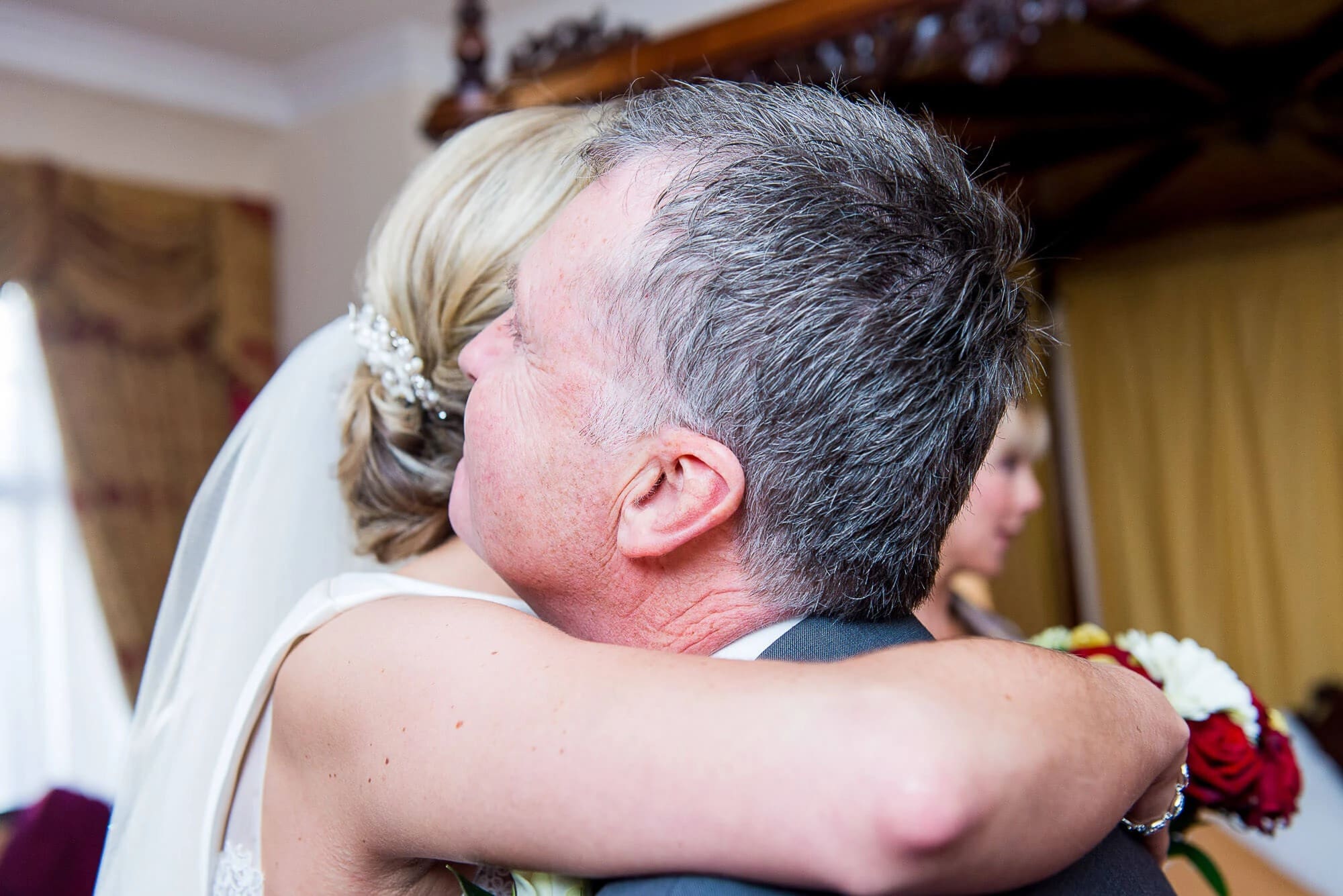 Bride and older man embracing in an emotional moment during wedding celebration. — Wedding at Stanhill Court Hotel, Surrey