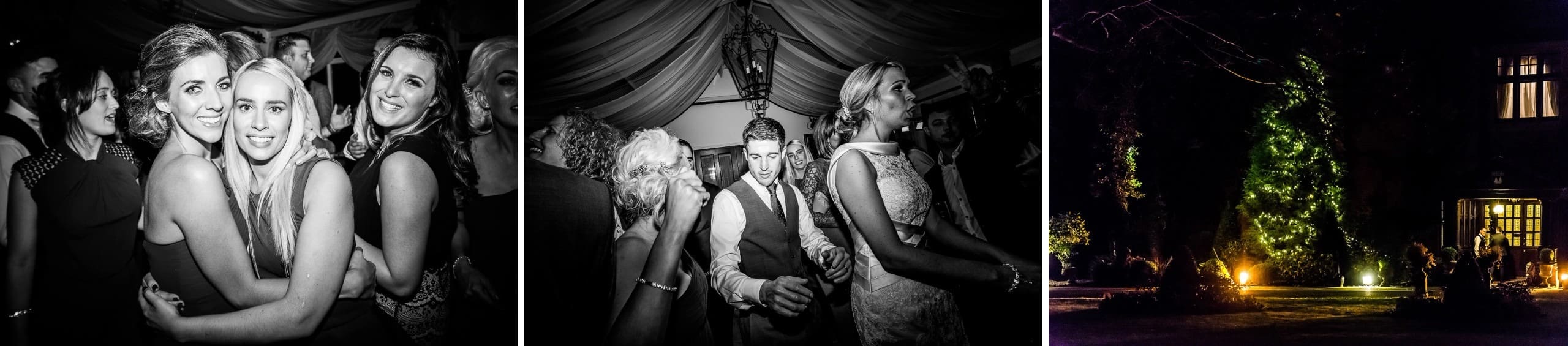Three women embracing and smiling together at an indoor evening event. — Wedding at Stanhill Court Hotel, Surrey