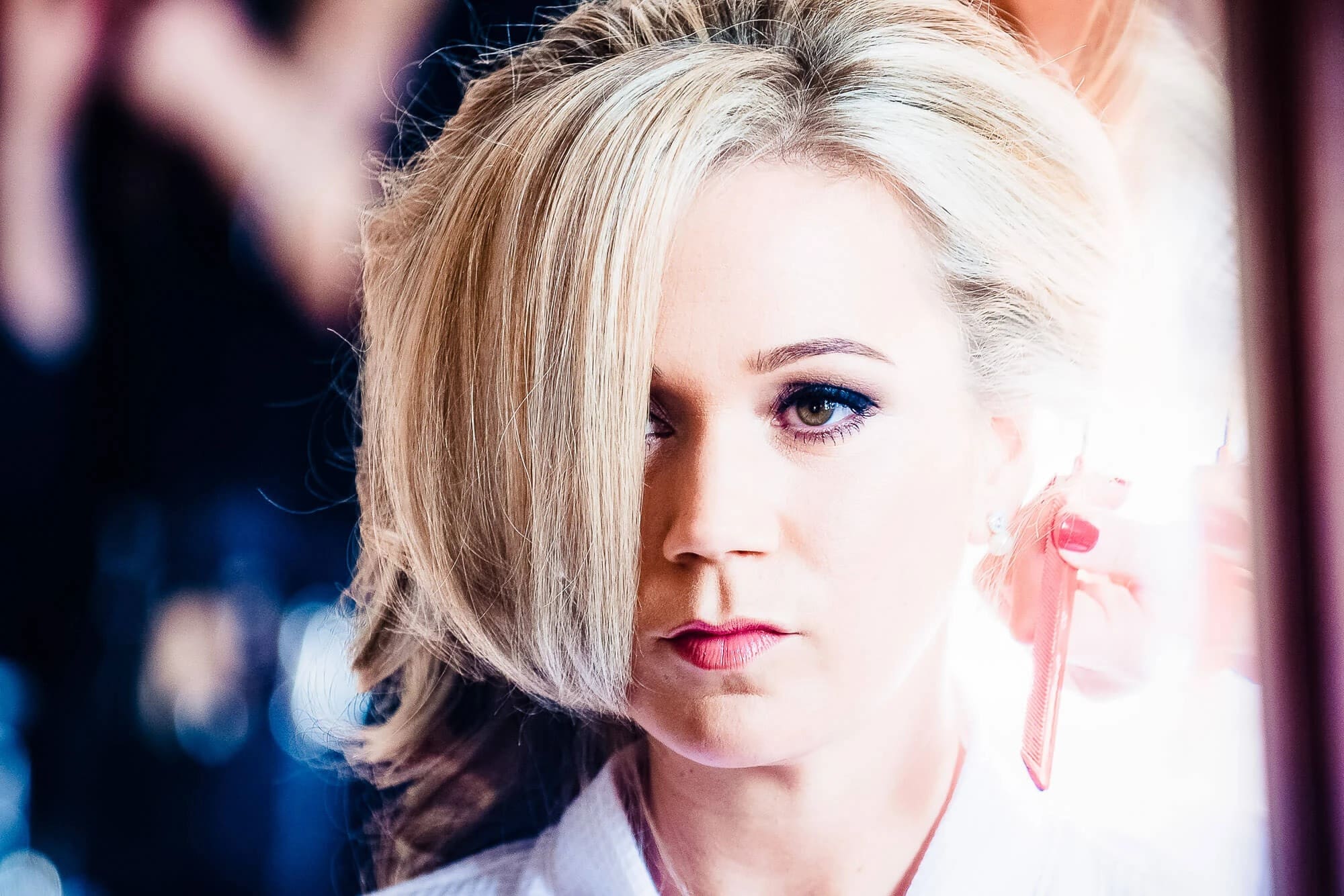 Woman with blonde bob gazing downward in contemplative pose, pink ribbon visible near her shoulder. — Wedding at Stanhill Court Hotel, Surrey