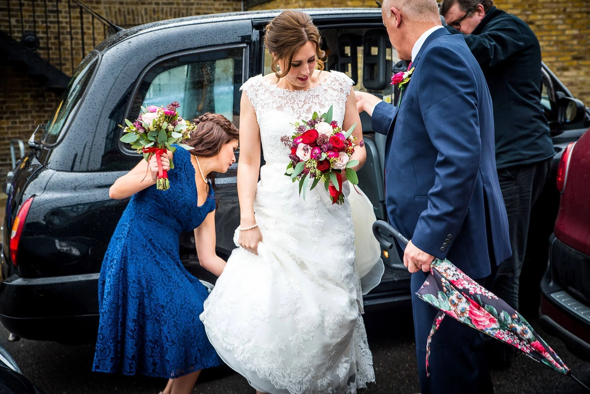 Bride exiting a car, assisted by family members holding her bouquet and dress. — Wedding at The Lodge Hotel Putney, London