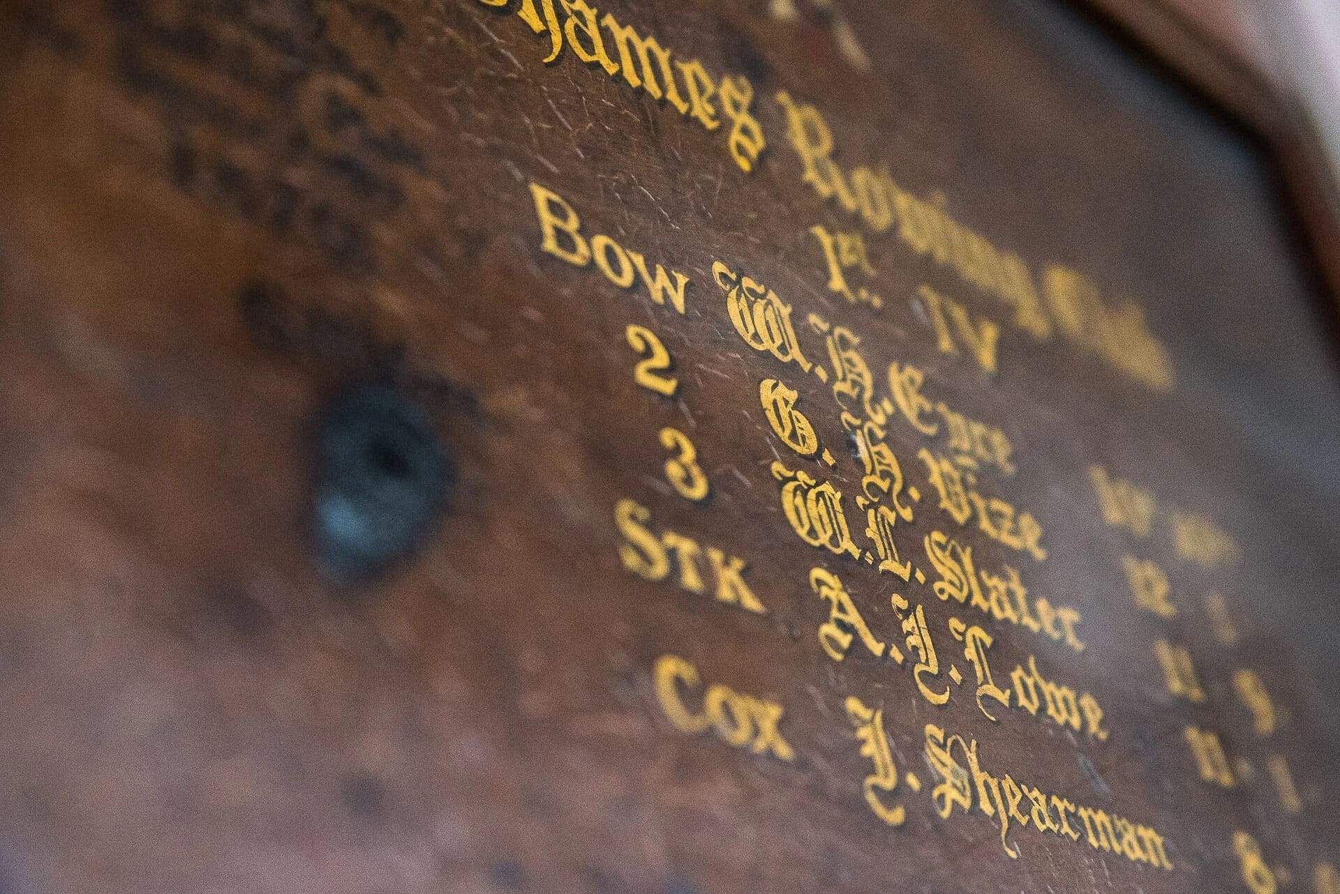 Close-up of engraved gold text on a dark leather surface, showing names and dates. — Wedding at The Lodge Hotel Putney, London