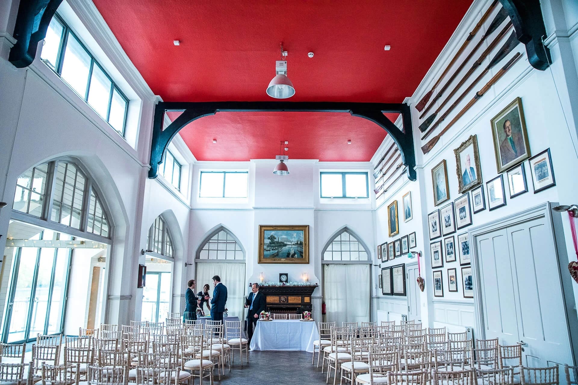 Guests seated in rows awaiting a ceremony in a bright, high-ceilinged hall with a striking red ceiling. — Wedding at The Lodge Hotel Putney, London