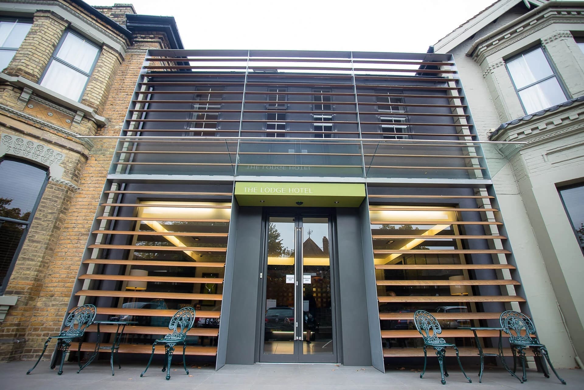 Modern building facade with illuminated horizontal slat entrance, photographed straight-on during evening. — Wedding at The Lodge Hotel Putney, London