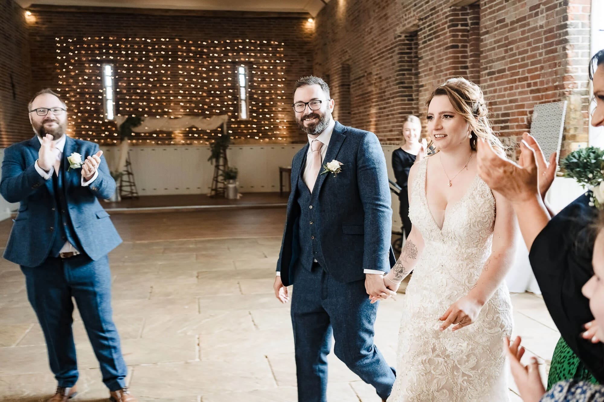 Bride and groom walk together down the aisle as guests applaud during the recessional. — Wedding at Manor Mews, Norfolk