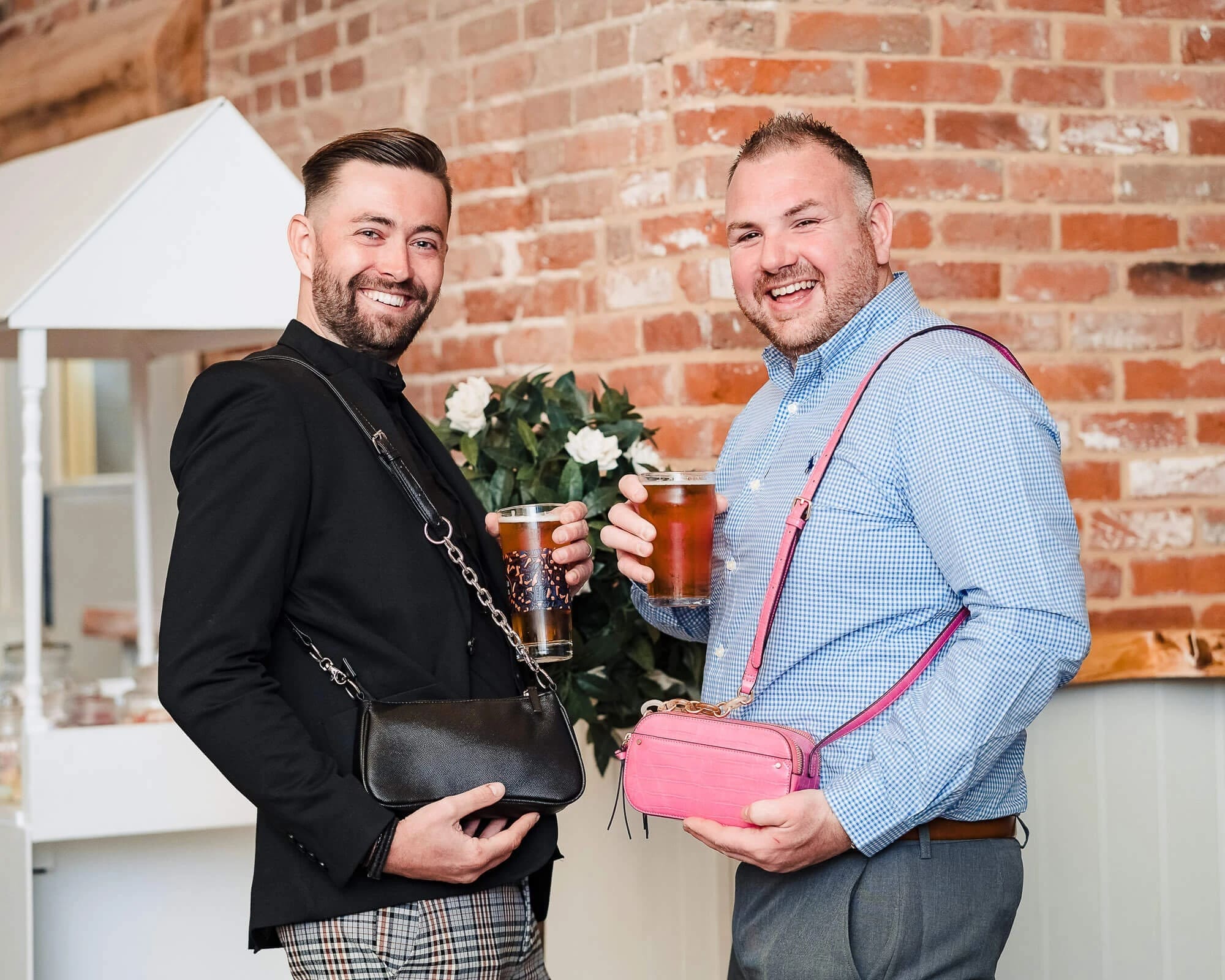 Two men toasting with drinks at an indoor event, smiling at the camera. — Wedding at Manor Mews, Norfolk