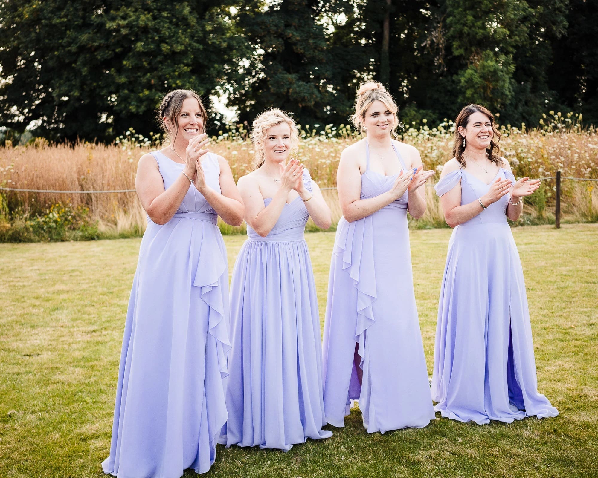 Four bridesmaids standing together in a line, smiling and posing for a formal portrait. — Wedding at Moulton Parish Church, Northamptonshire