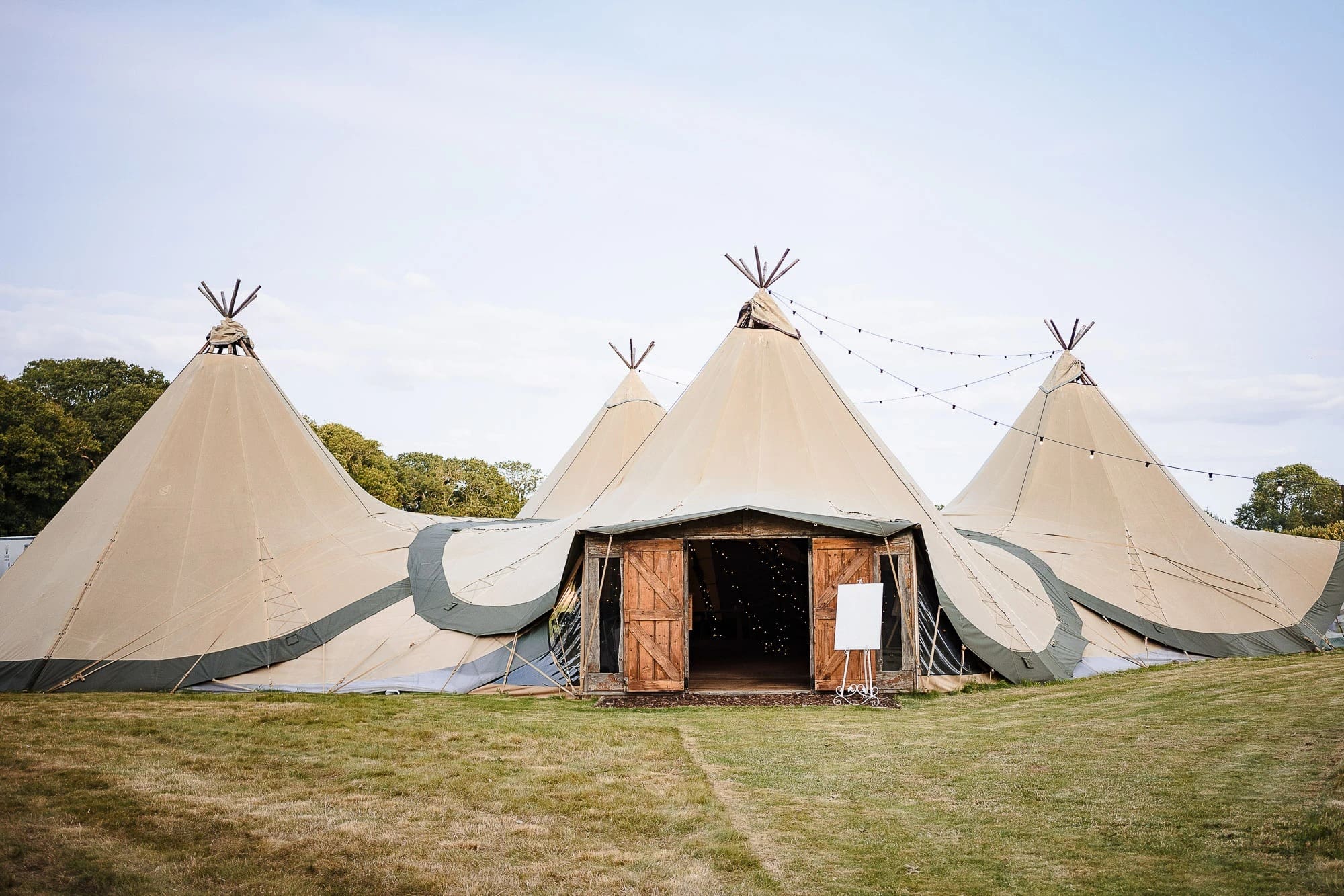 Glamping setup with multiple bell tents arranged in a field, ready for guests. — Wedding at Moulton Parish Church, Northamptonshire