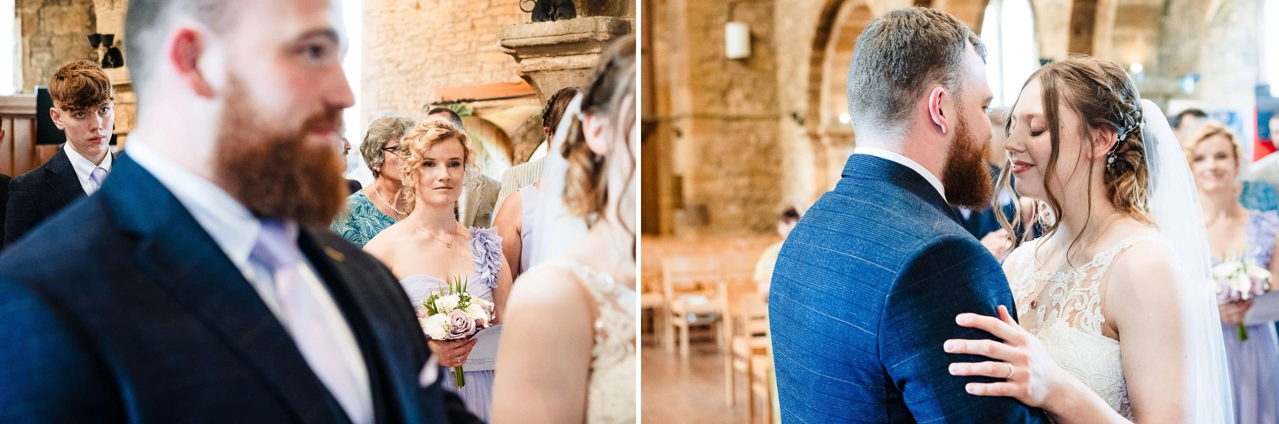 Wedding guests and wedding party members standing together during ceremony, with bearded man in navy suit in sharp focus in foreground. — Wedding at Moulton Parish Church, Northamptonshire