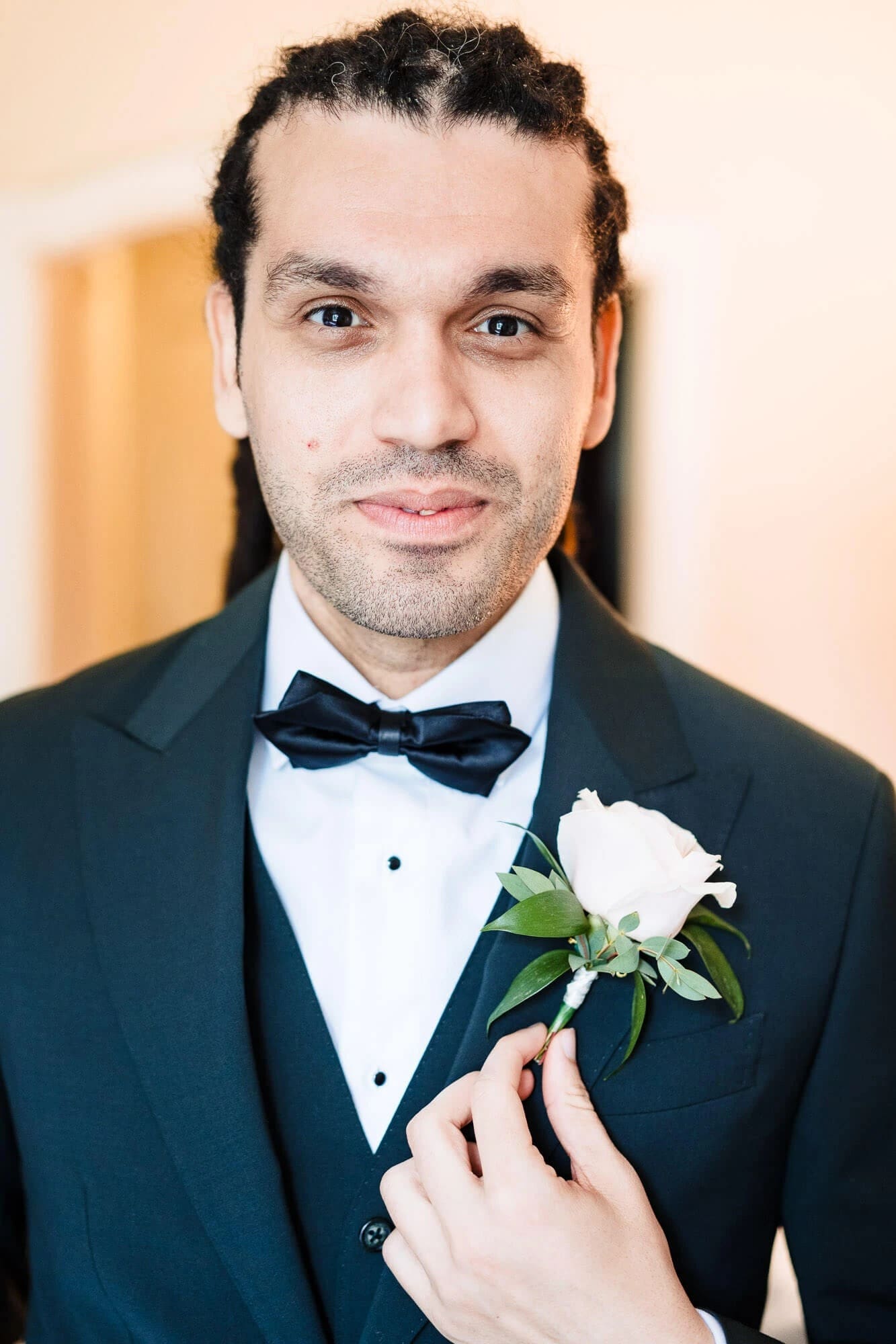 Groom posing formally for a portrait, holding his boutonniere and gazing directly at camera. — Wedding at Sprowston Manor Hotel, Norfolk