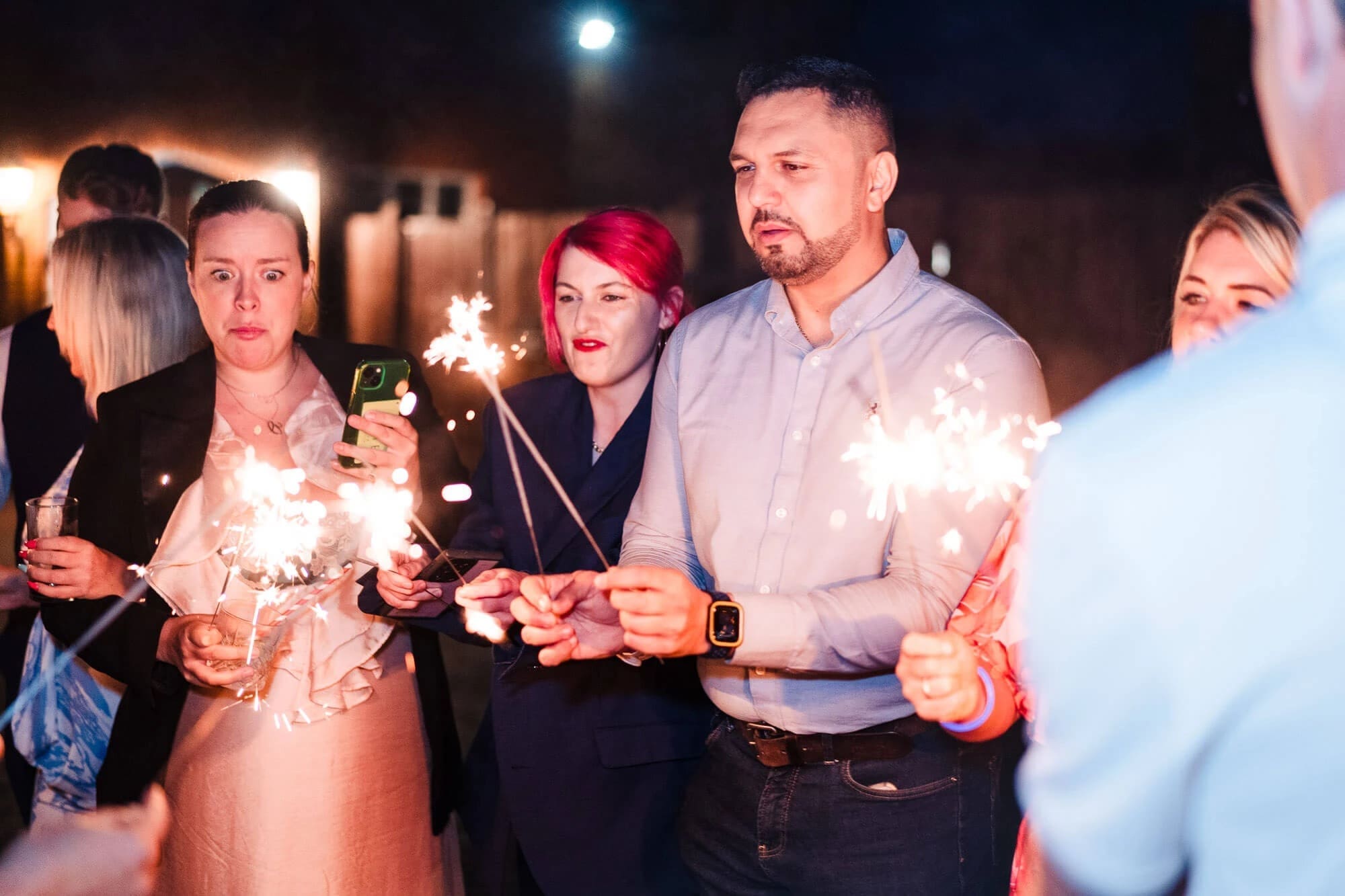 Group of guests holding sparklers at night during an outdoor celebration. — Wedding at Sprowston Manor Hotel, Norfolk