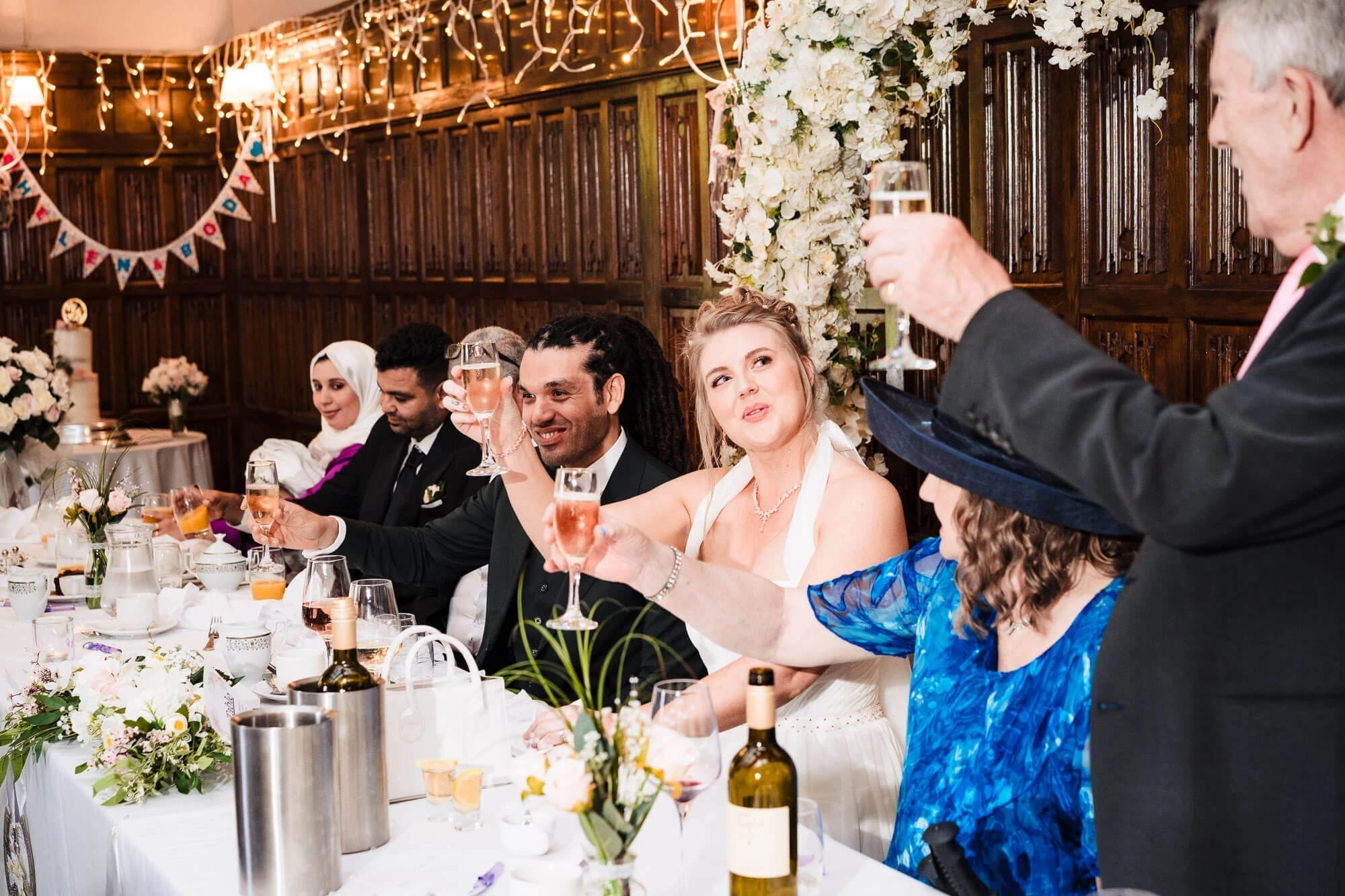 Wedding guests raising glasses in a toast during the reception dinner. — Wedding at Sprowston Manor Hotel, Norfolk